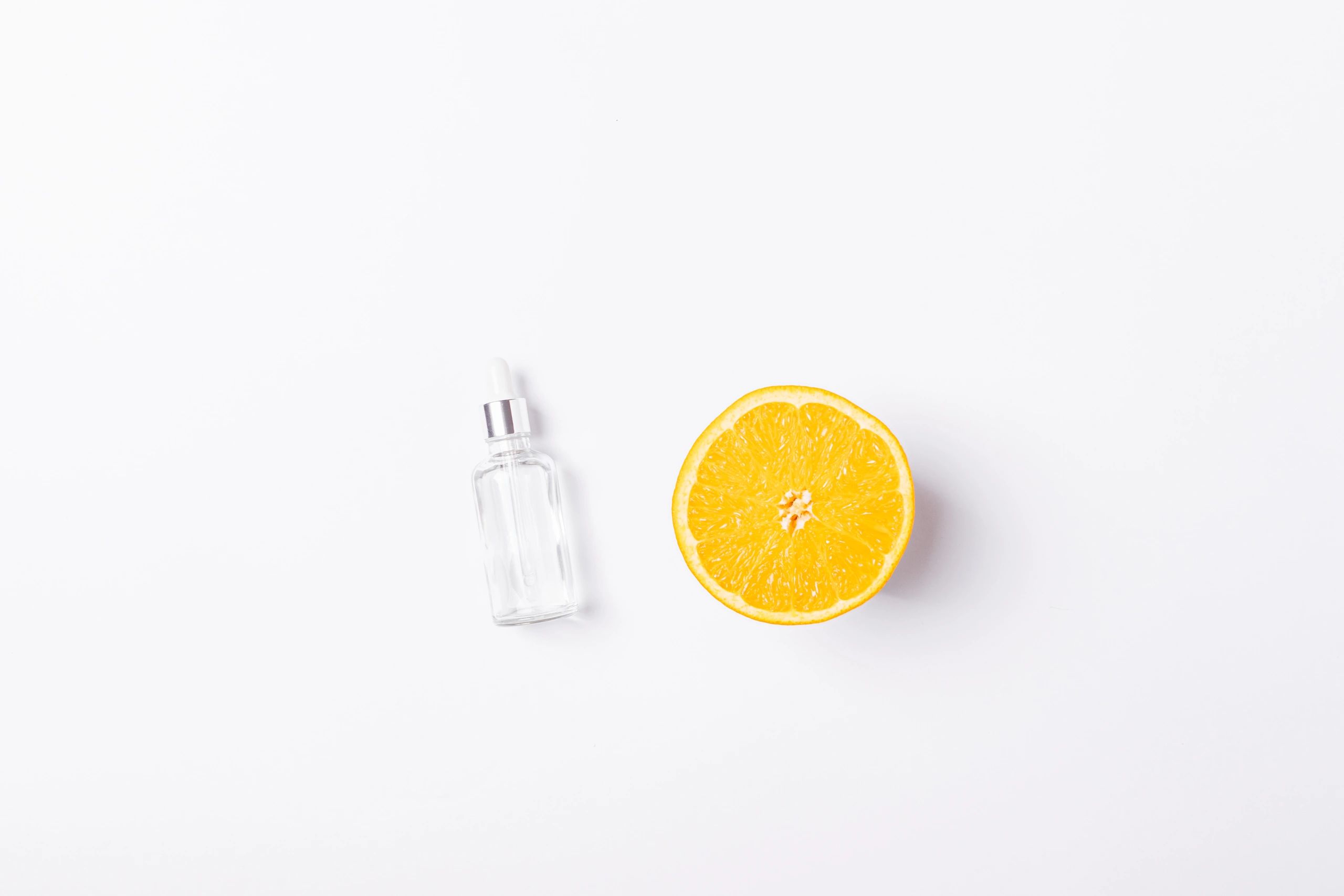 Vitamin C serum with orange fruit on a white background flat lay