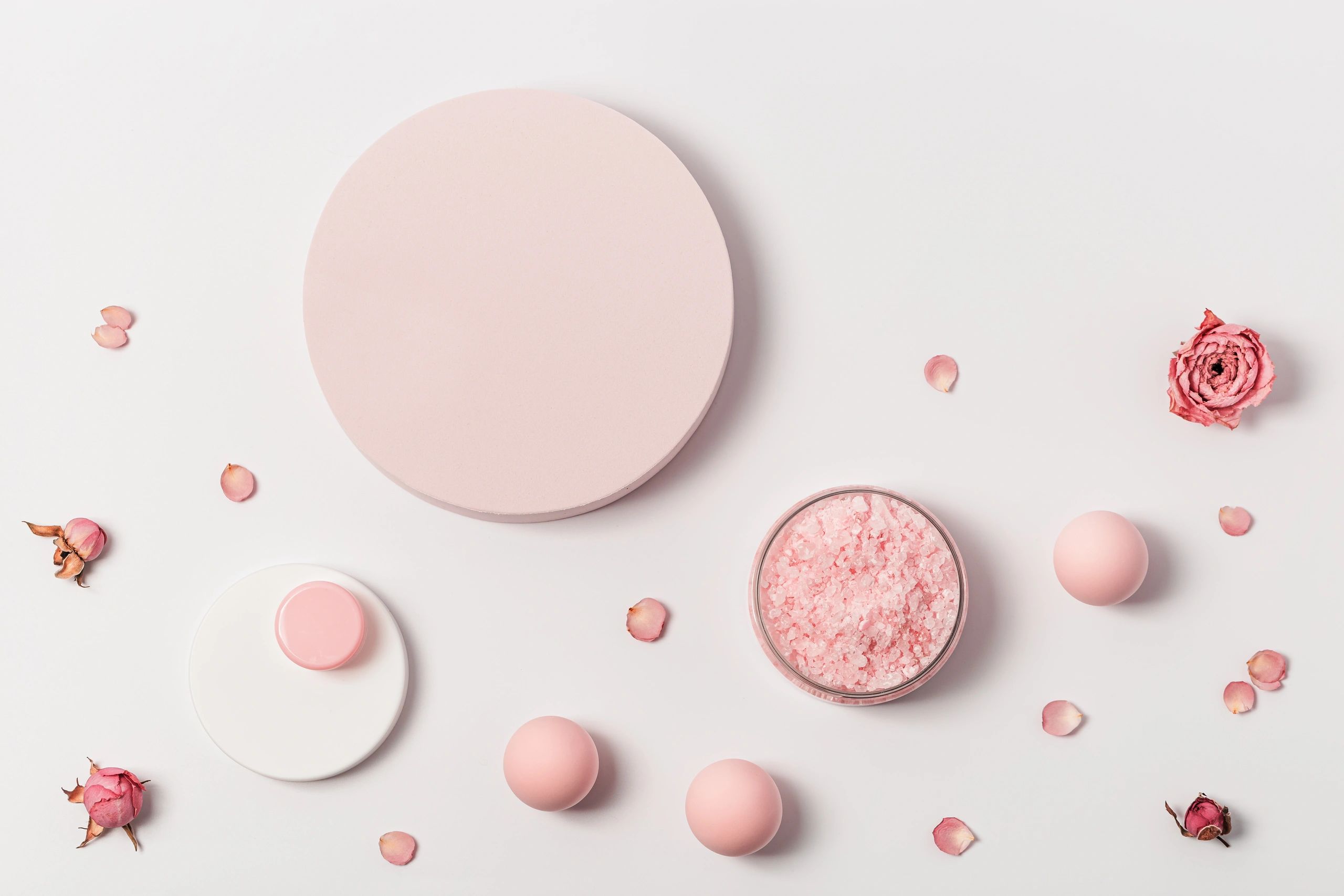 Rose sea salt jar with bath products on a white background