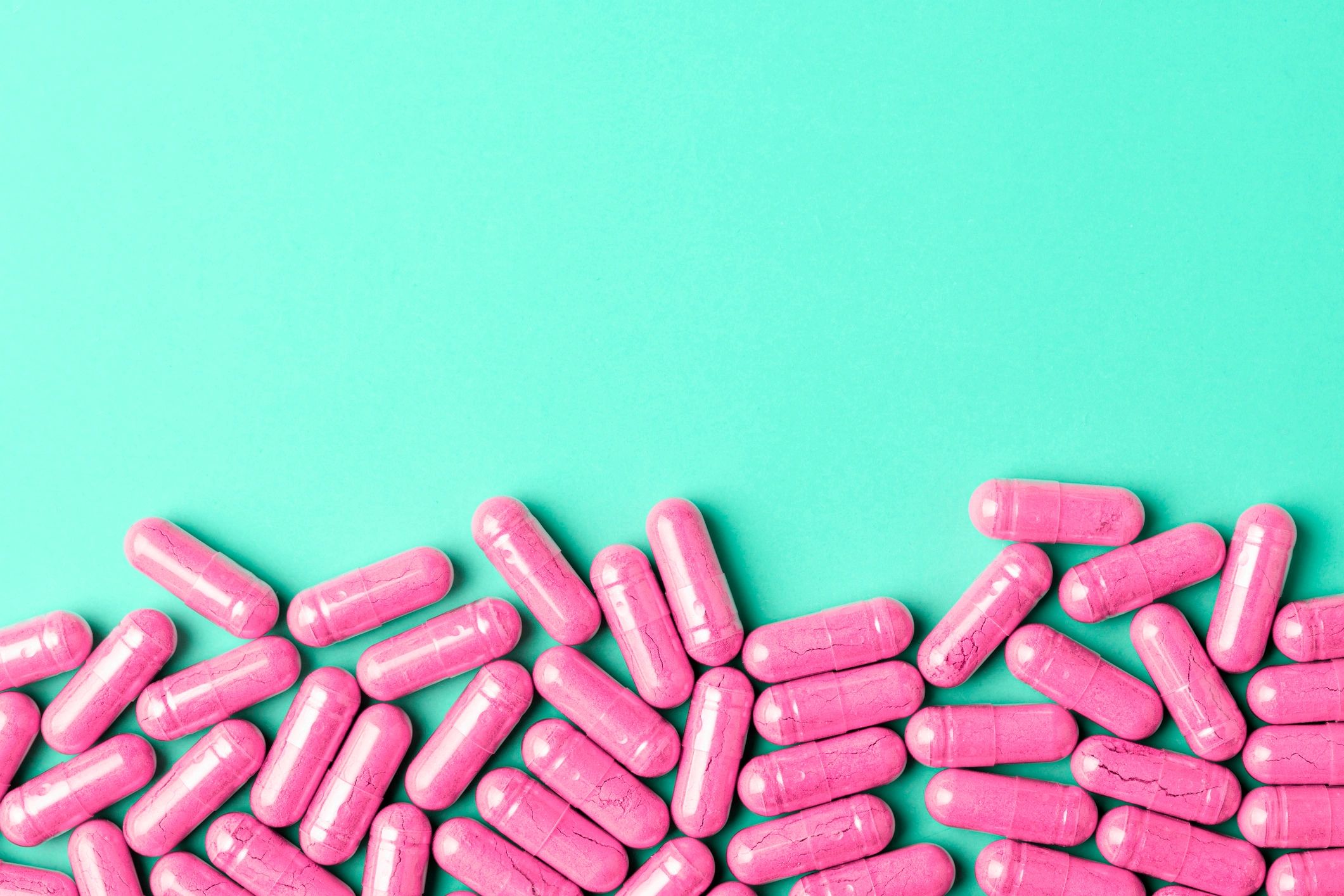 Pink capsules on mint background with copy space
