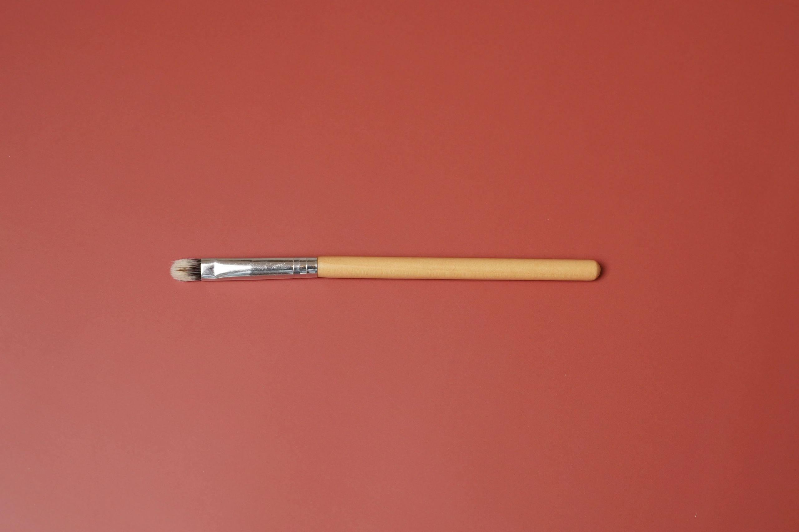 Minimal makeup brush on dusty rose background